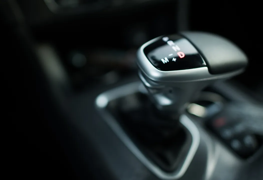 Vista superior de la palanca que muestra con detalle las letras de las velocidades de un carro automático en la parte frontal Vista superior de la palanca de velocidades de un carro automático enfocada en las letras de los cambios