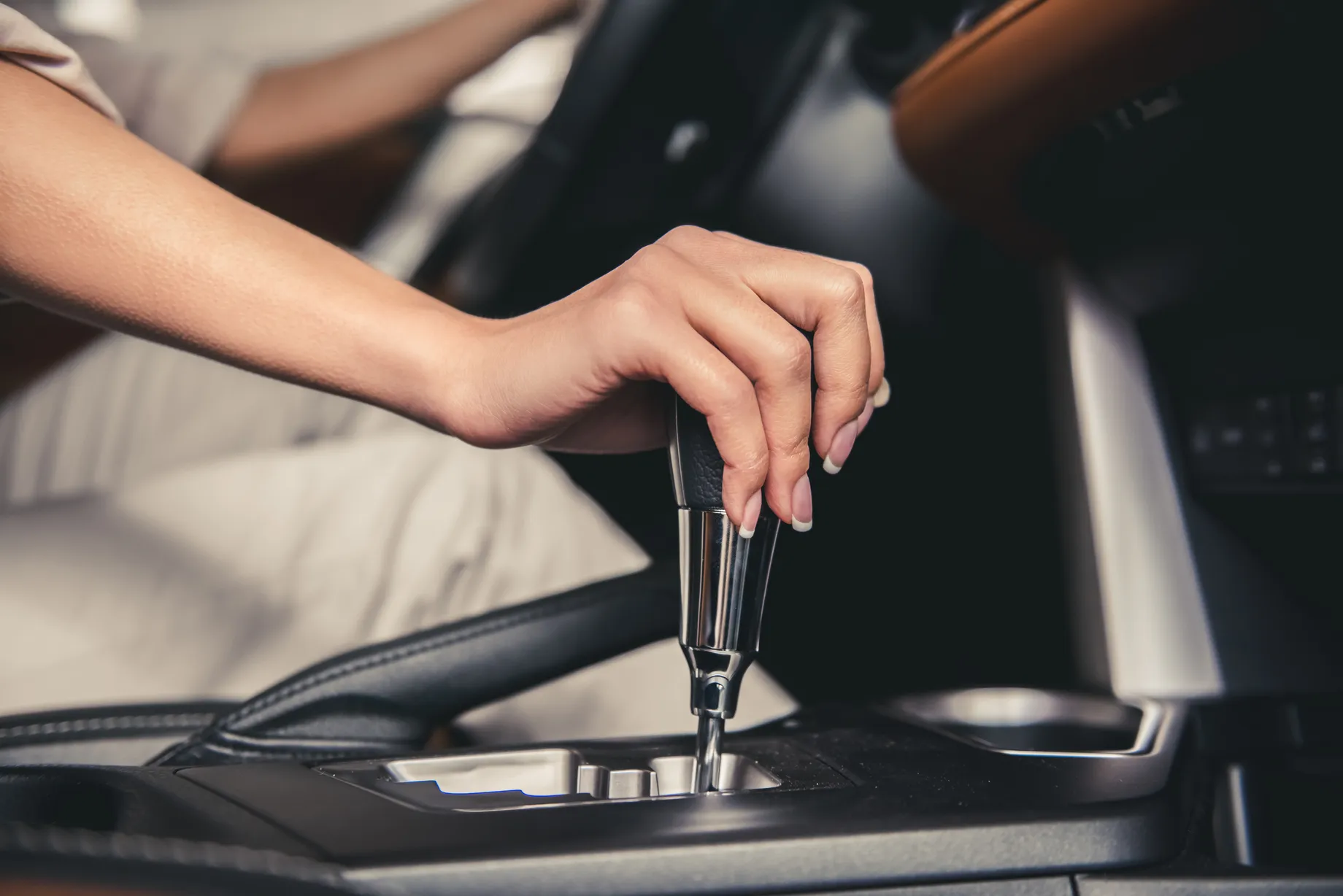 Mano femenina ajustando la palanca de velocidades de un carro automático al arrancar el vehículo para iniciar la conducción Mano de una mujer moviendo la palanca para ajustar las velocidades de un carro automático al encender el auto