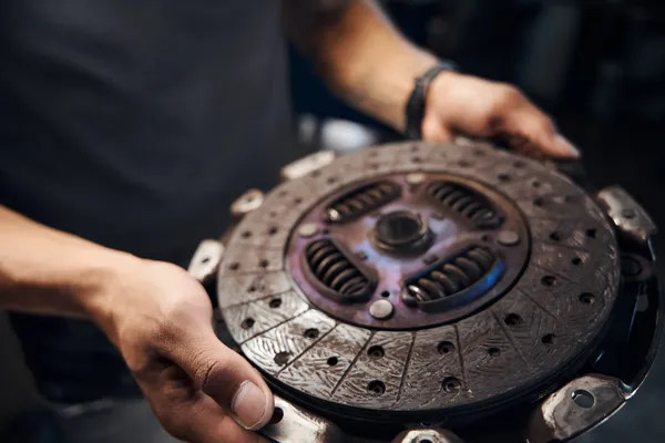 Embrague con desgaste evidente sostenido por un mecánico, pieza clave para entender cómo saber cuando una transmisión estándar está fallando