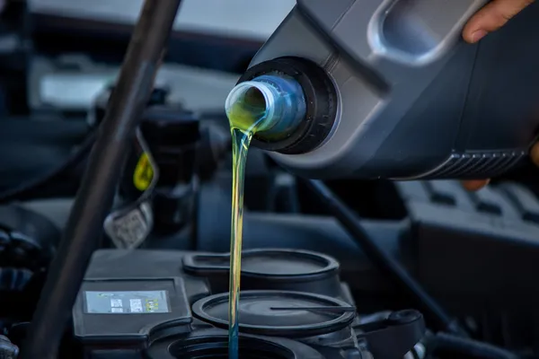 El líquido de color amarillo verdoso del aceite para transmisión automática fluye de la botella directamente hacia la parte superior del motor.