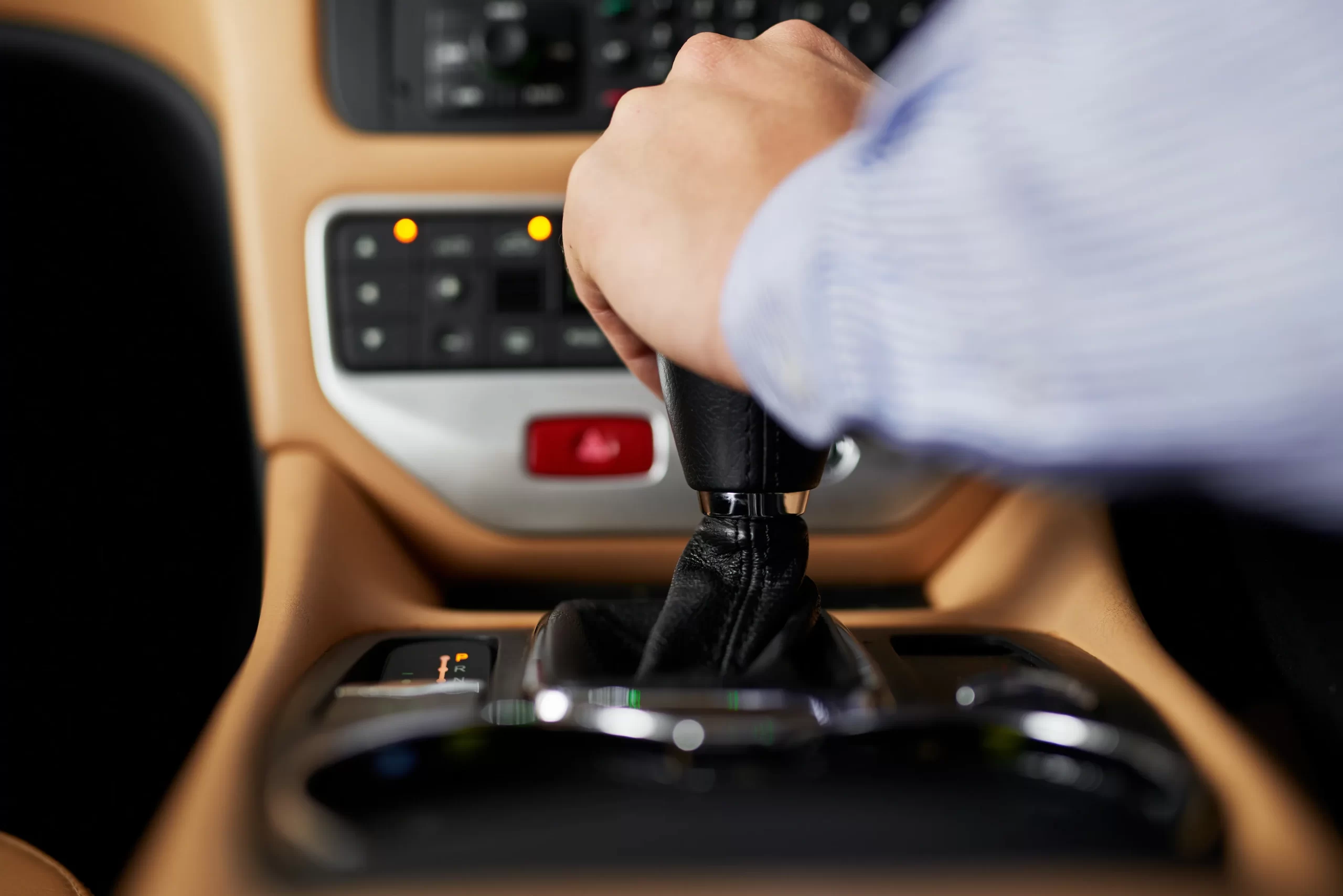 Conductor sujetando la palanca; si mi carro automático se queda en una velocidad y no sube, podría ser el sensor.
